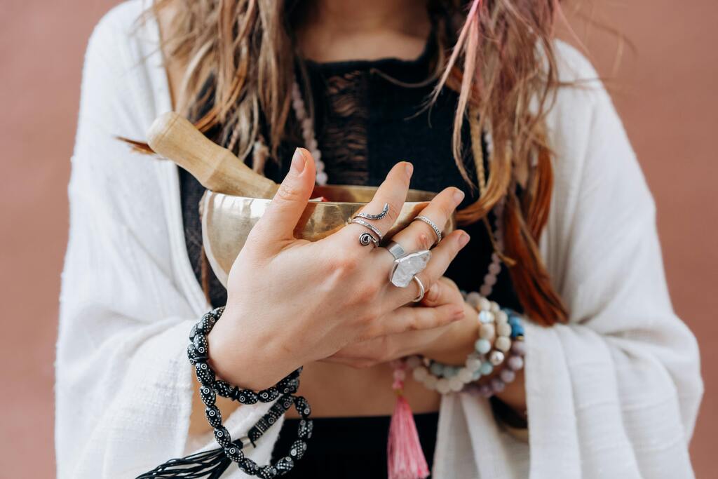 A photograph of a woman holding a brass Tibetan singing bowl