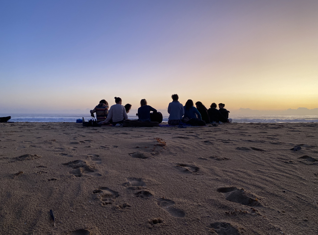A photograph of people on a beach at sunset